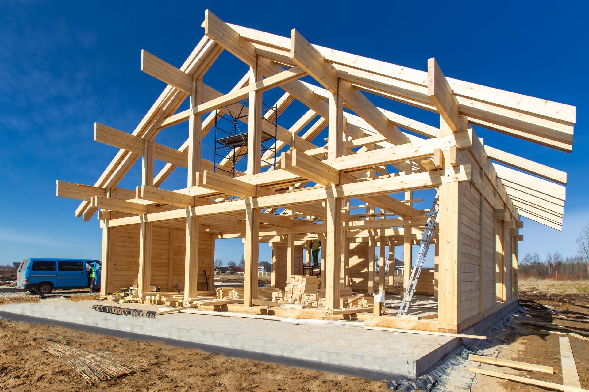 Wooden timber frame house under construction with roof trusses on concrete foundation. Wooden timber frame house under construction with roof trusses on concrete foundation.