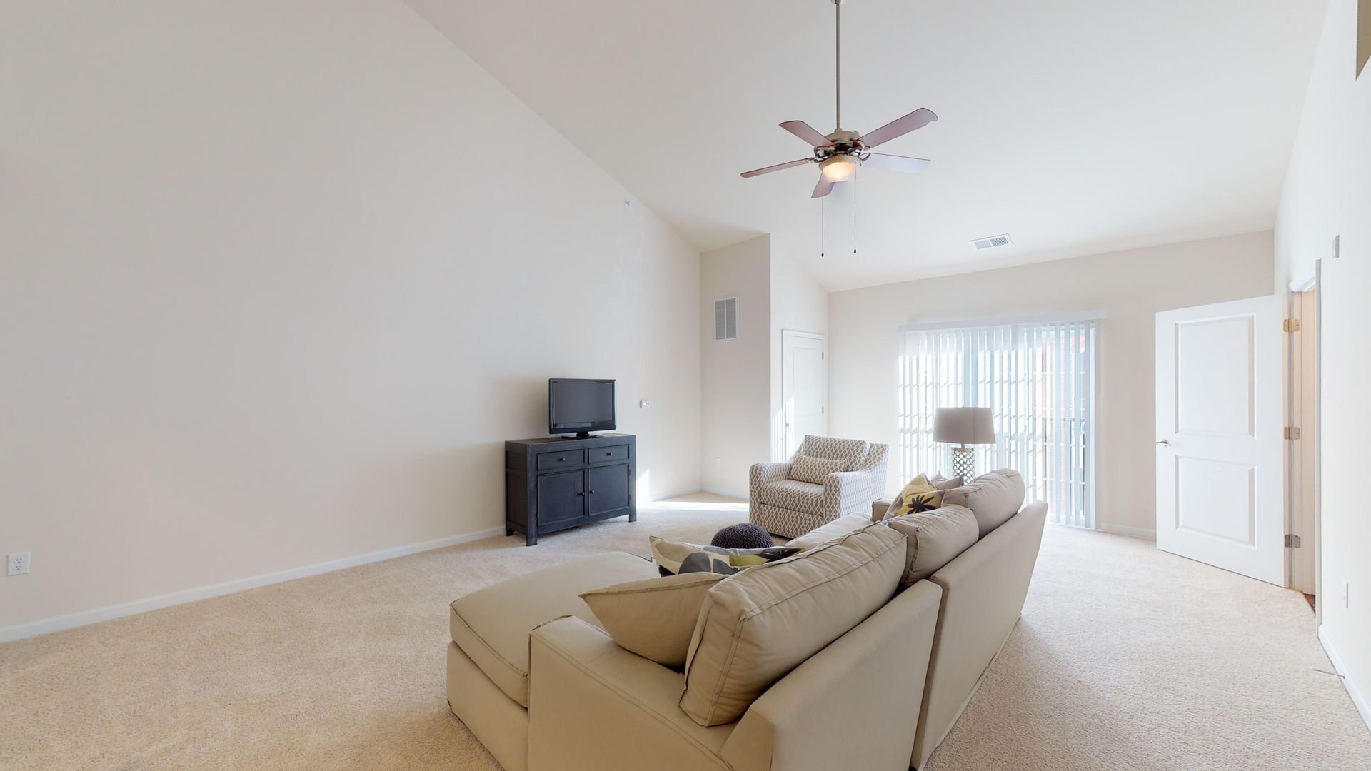 A living room with a couch , chair , television and ceiling fan.