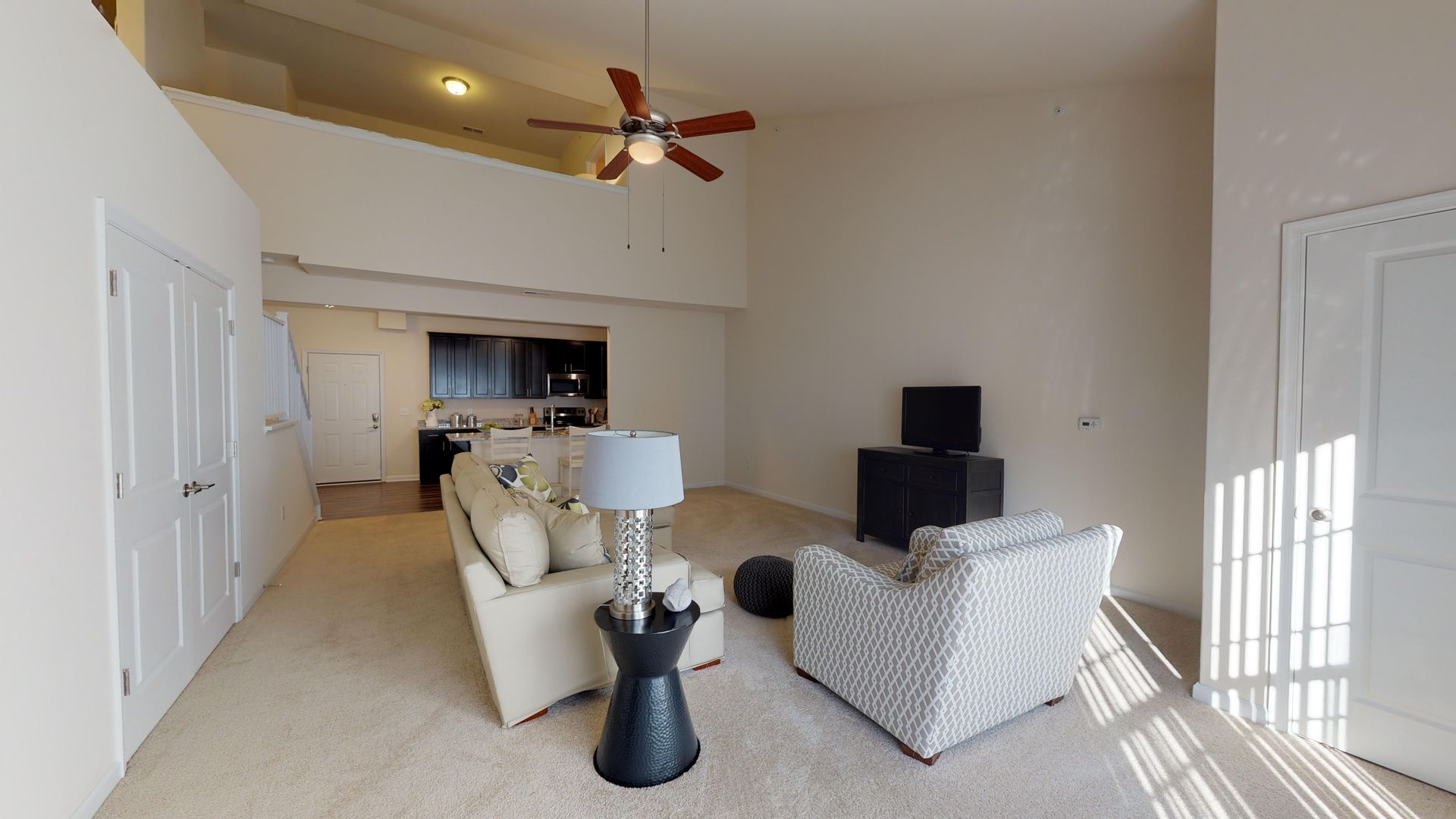 A living room with a couch , chair , lamp and ceiling fan.