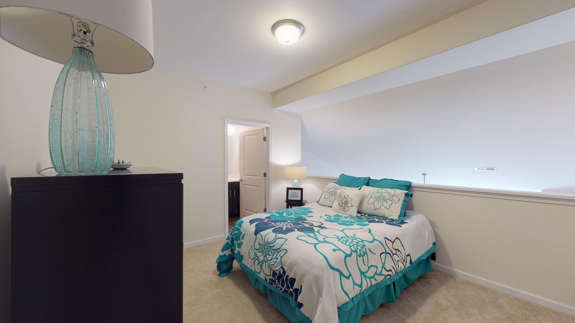 A bedroom with a large bed and a lamp.