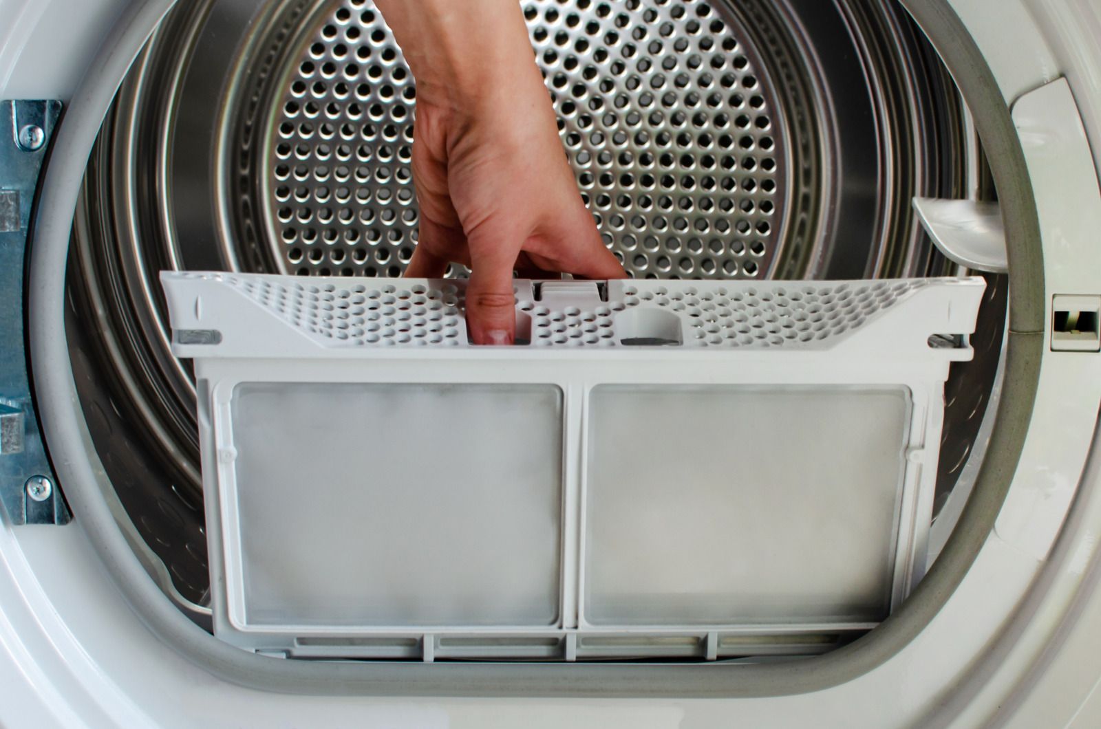 Hand placing a lint filter into an open dryer drum