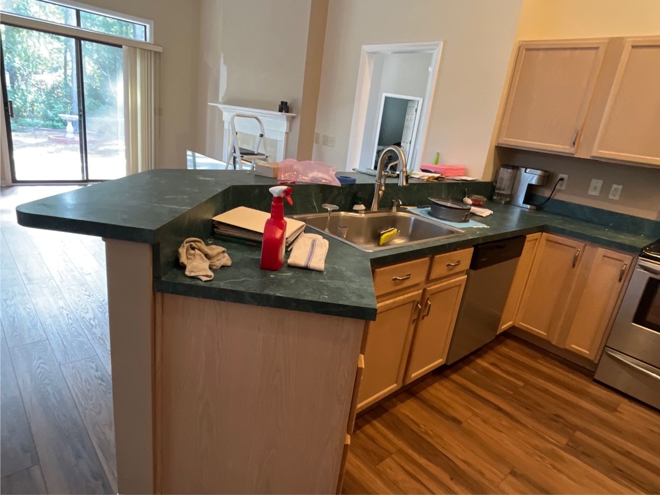 Kitchen with black countertops, wood cabinets, stainless appliances, and a sink beside a breakfast bar.