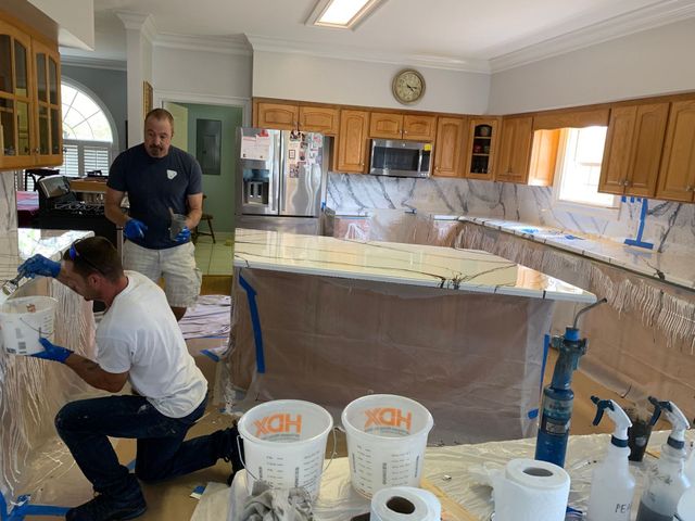 Workers installing cabinets and countertops in a kitchen under renovation