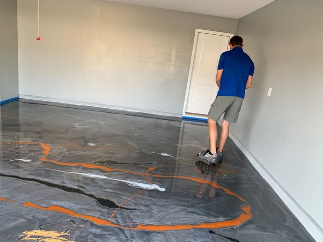 Person walking on a freshly coated concrete floor in an empty room with gray walls.