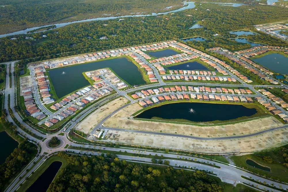 Aerial view of a planned lakeside neighborhood with curved streets, houses, and large water features