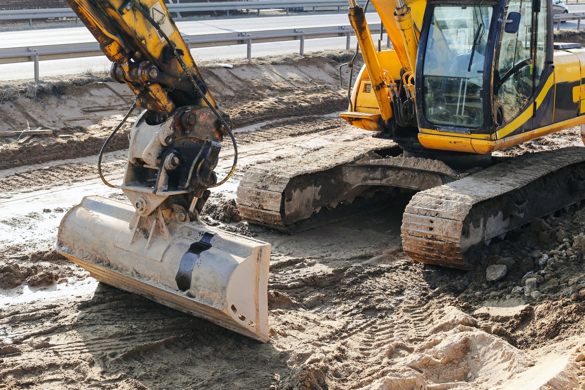 Yellow excavator digging muddy ground at a construction site