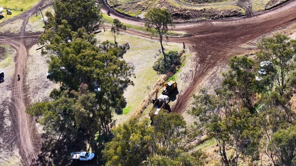 Aerial view of a dirt track winding through trees, with a vehicle on the path.