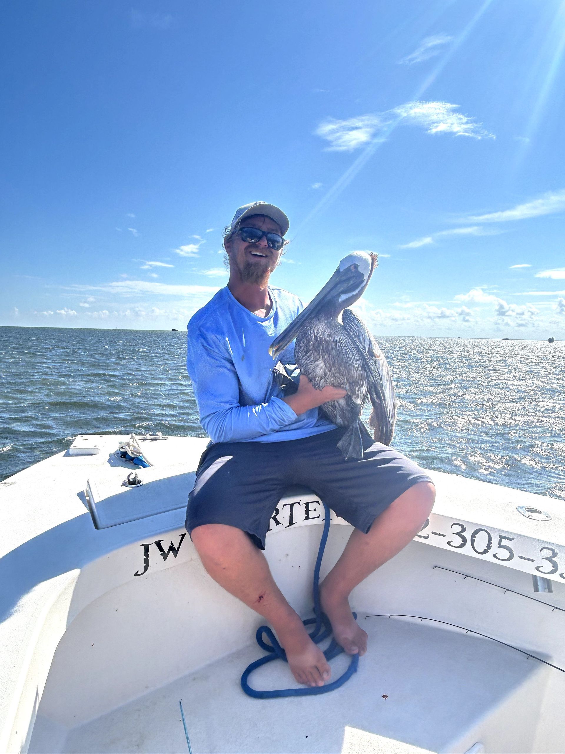 Man on a boat holding a large fish under a sunny blue sky