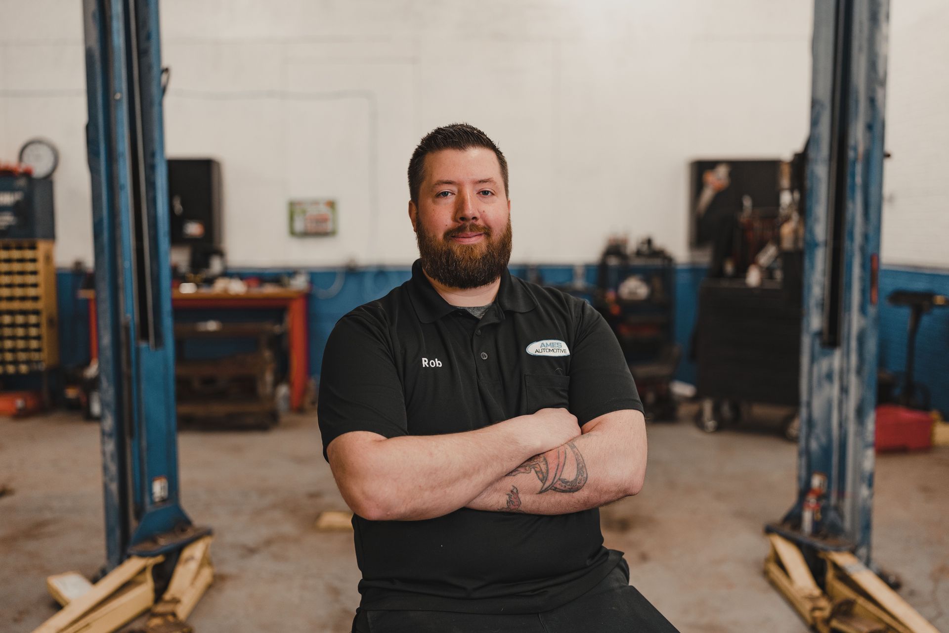 Mechanic standing with arms crossed in a garage between vehicle lifts