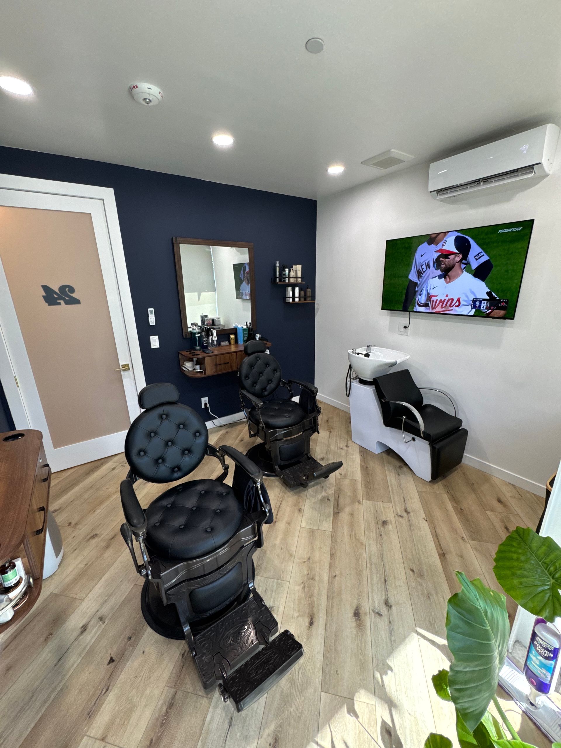 Blue-walled salon with styling chairs, mirror, shelves, and a wood countertop in a small room