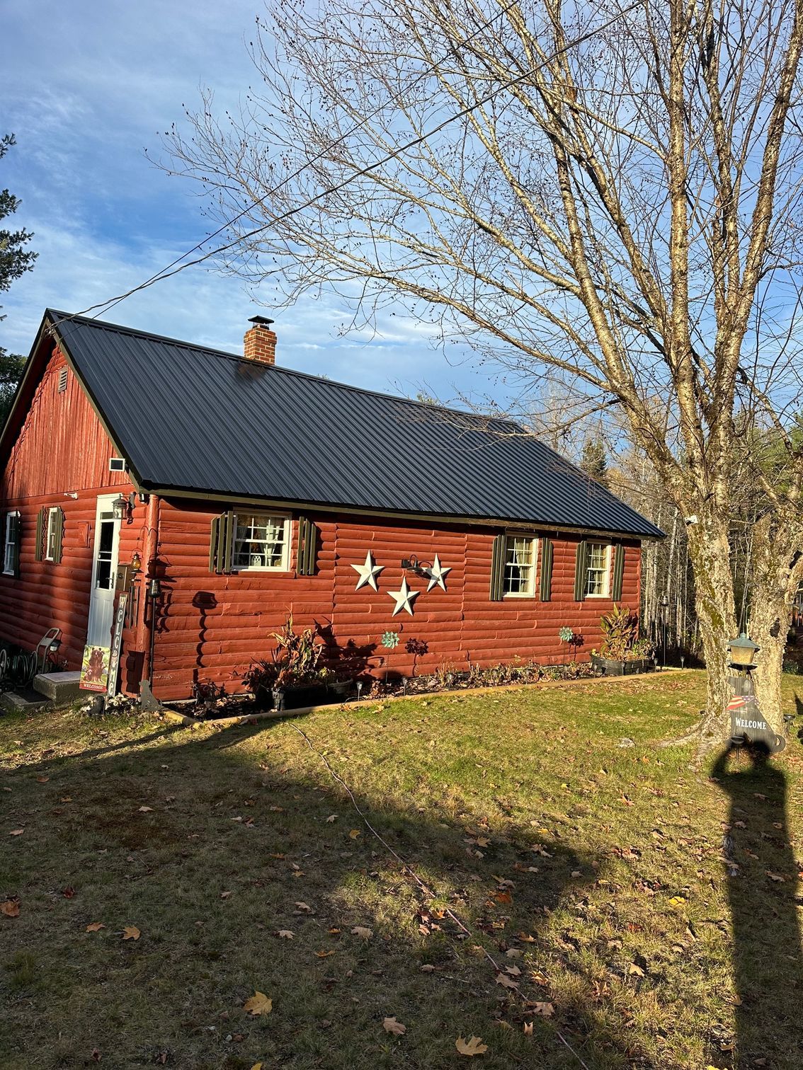 Red cottage with black roof, white trim, and three star decorations on the front.