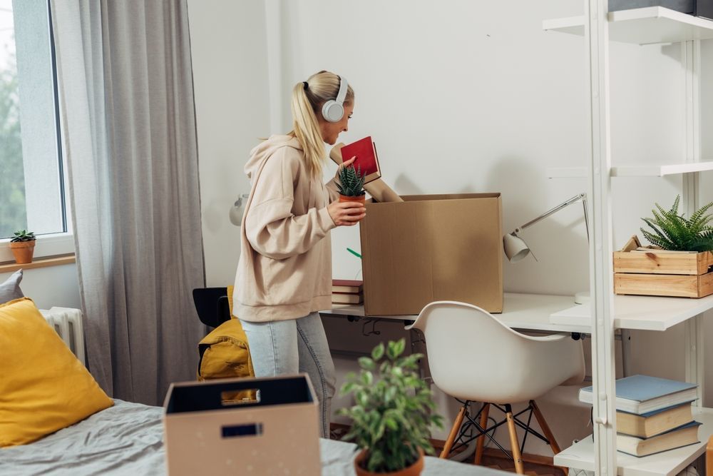 A college student is unpacking her stuff from boxes.