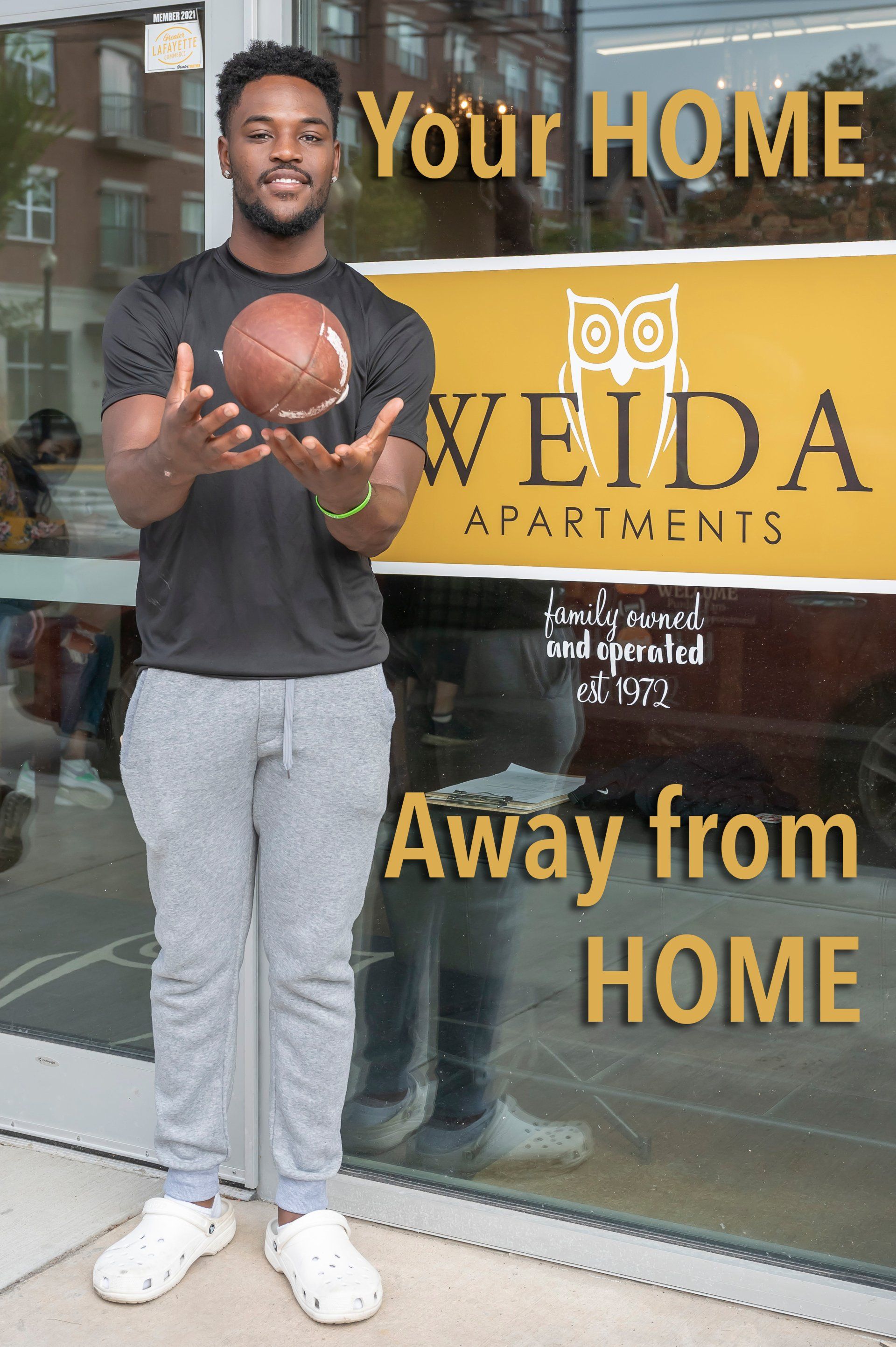 Purdue student holding football in front of Weida office front entrance - 