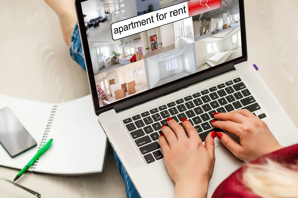 Woman hands on laptop keyboard searching for apartments to rent.