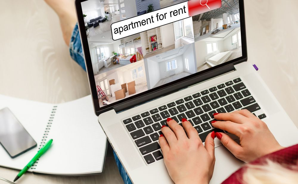 Woman hands on laptop keyboard searching for apartments to rent.