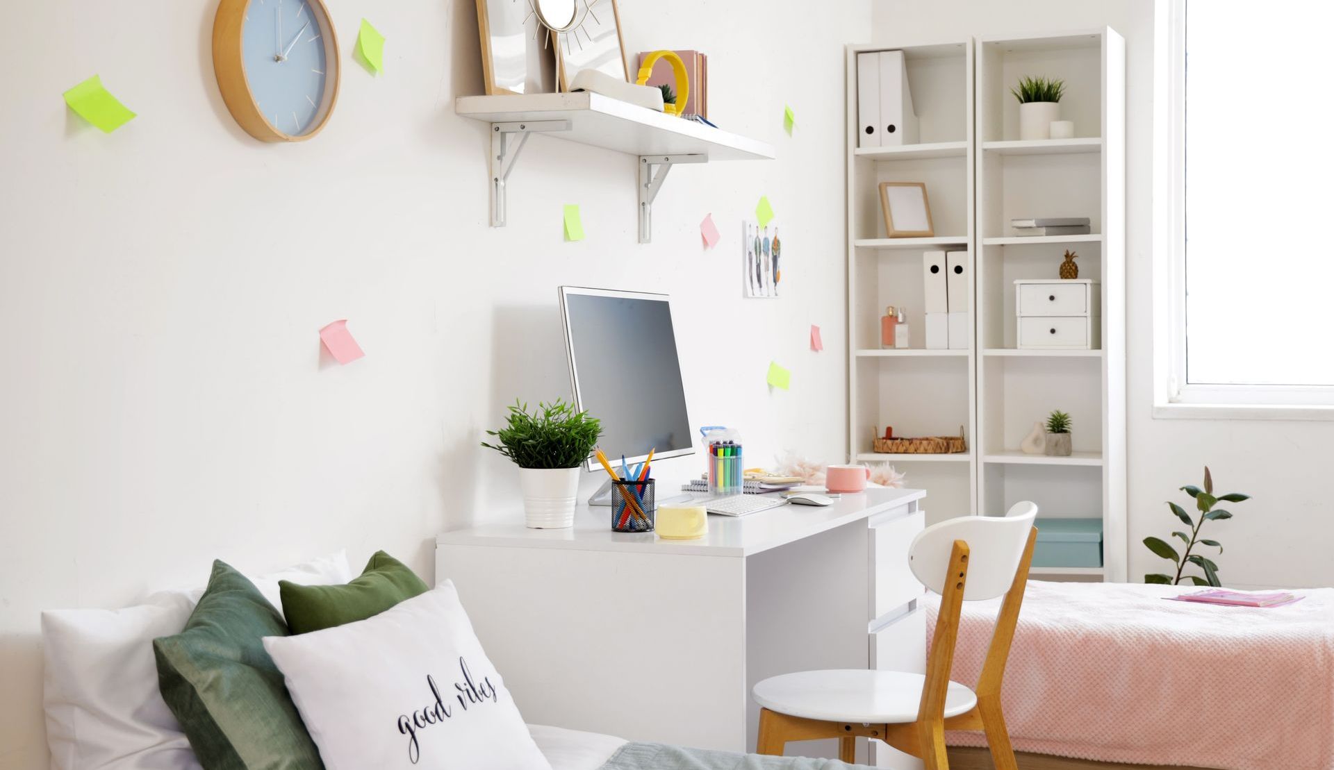 Dorm room with two beds, a desk and items hanging from the wall.