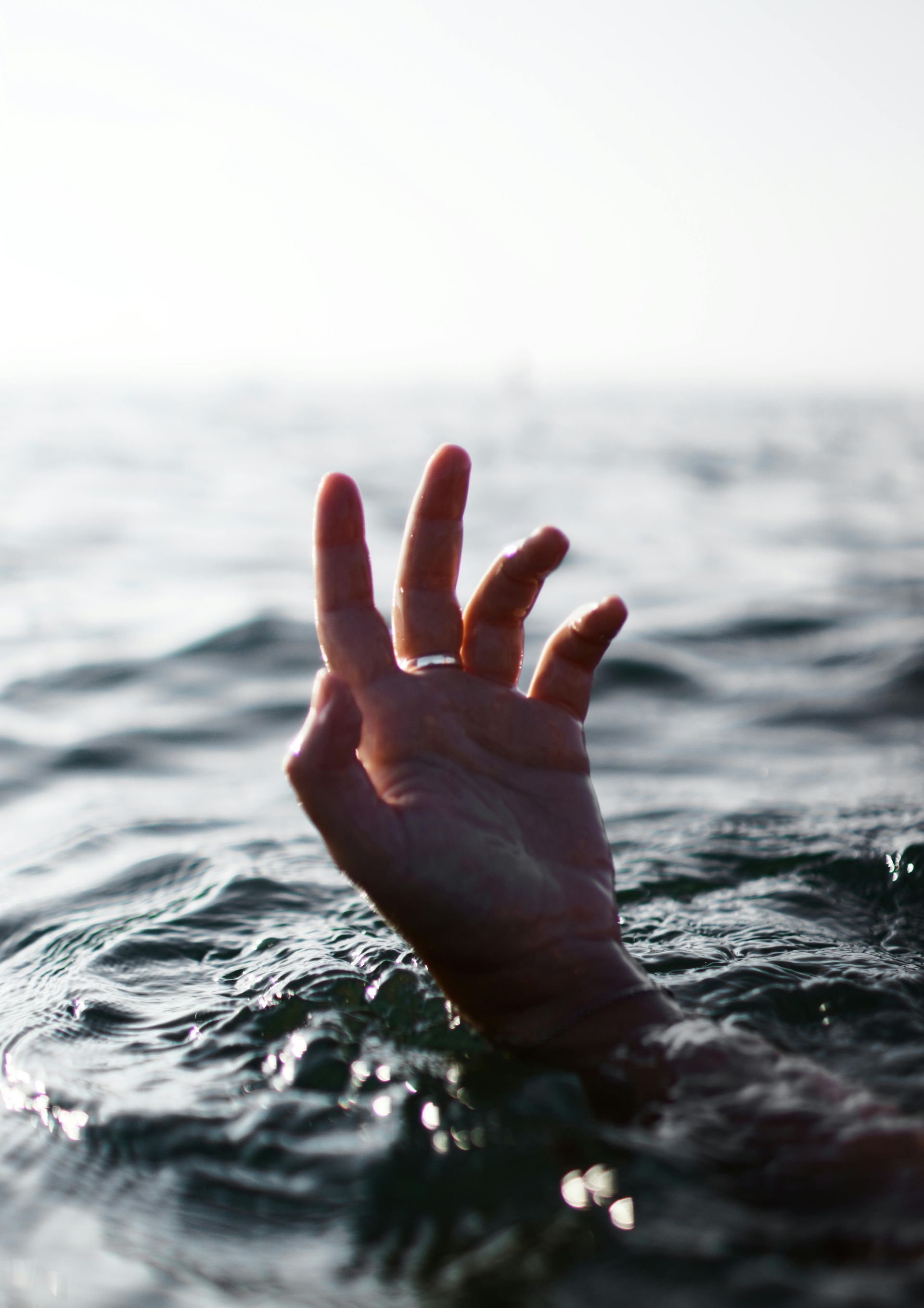 A hand is sticking out of the water in the ocean.