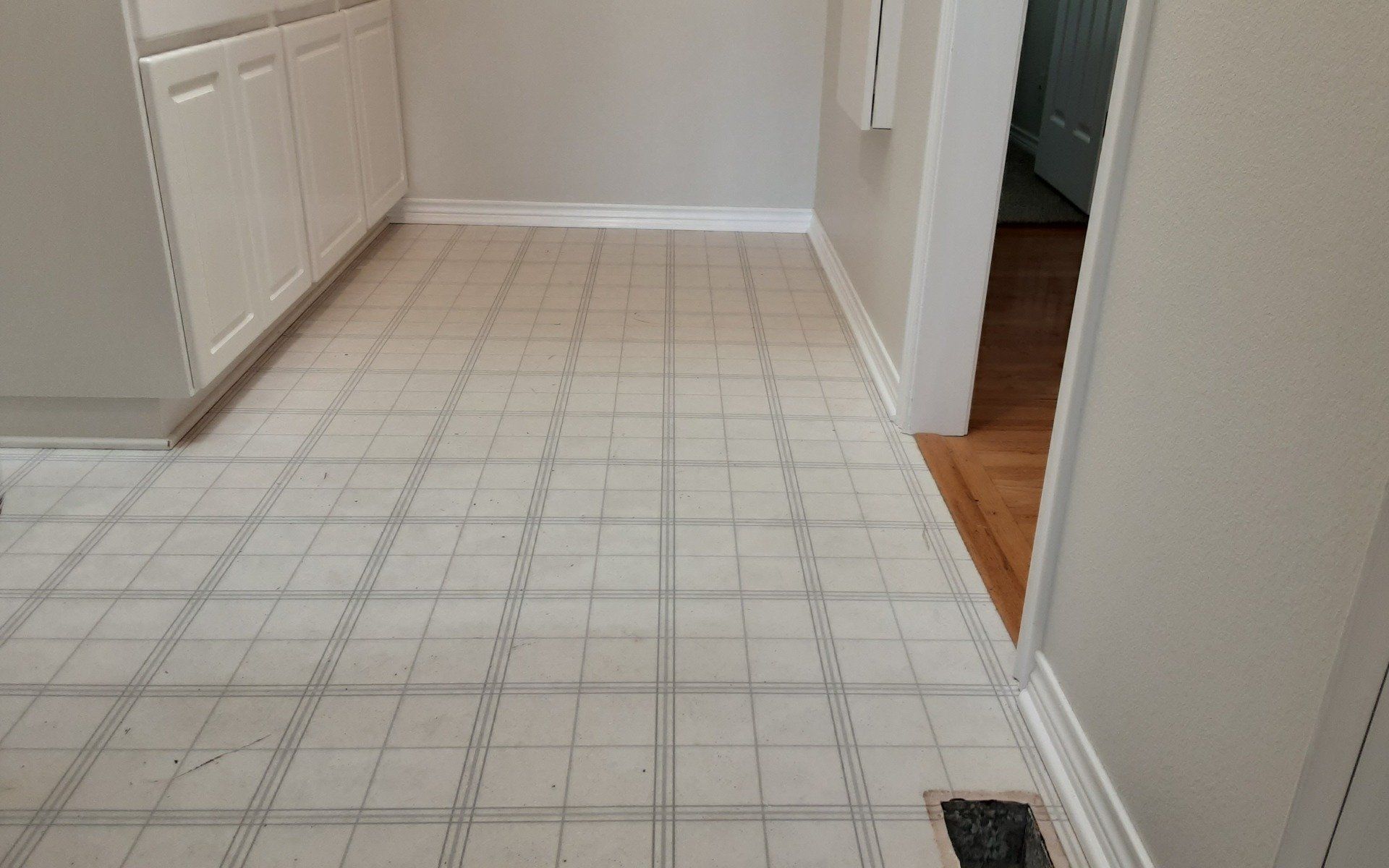 White tiled hallway with cabinets on the left and an open doorway on the right