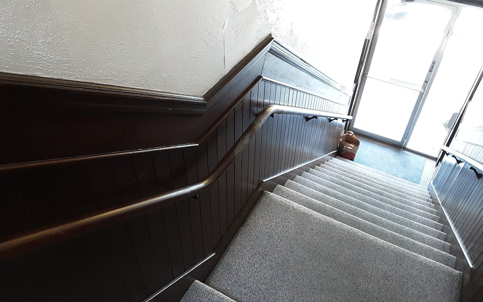 Stairwell with dark wood banister and metal railing beside a windowed landing
