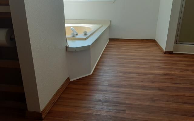 Empty room with wood-look flooring and a corner sink beneath a window
