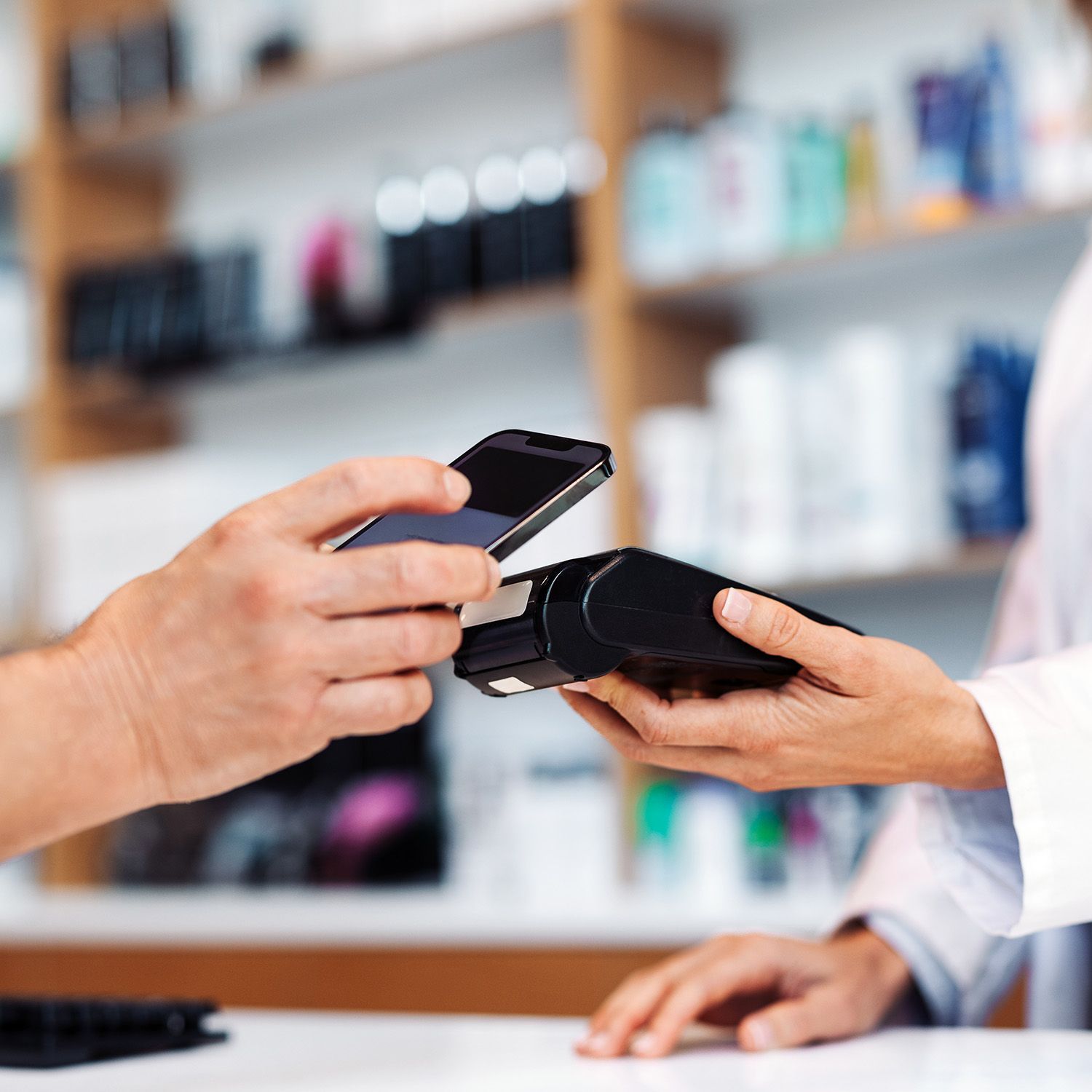 A person is paying with a cell phone in a pharmacy.