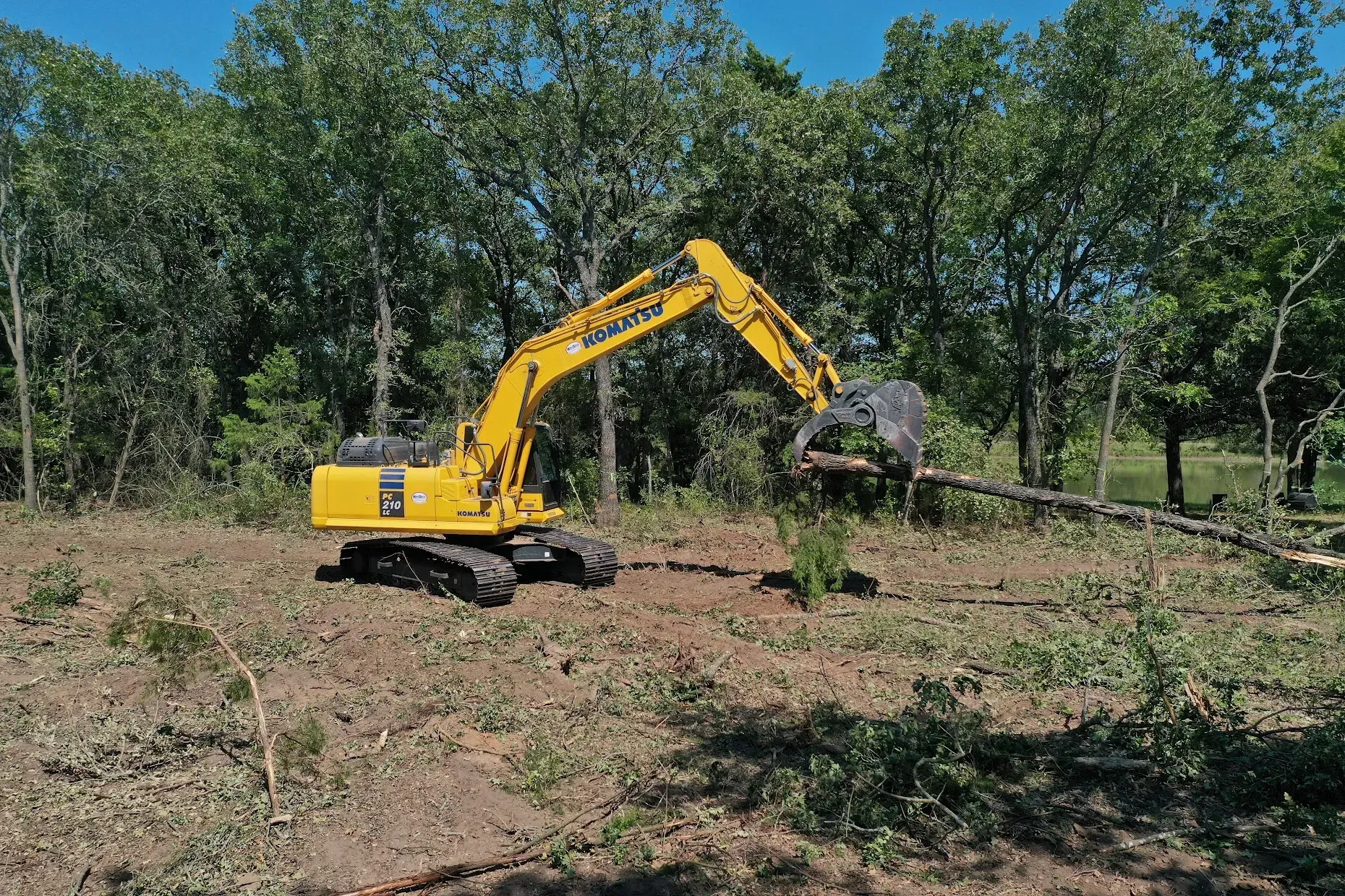 An excavator clearing land and removing brush near Conroe, Texas.