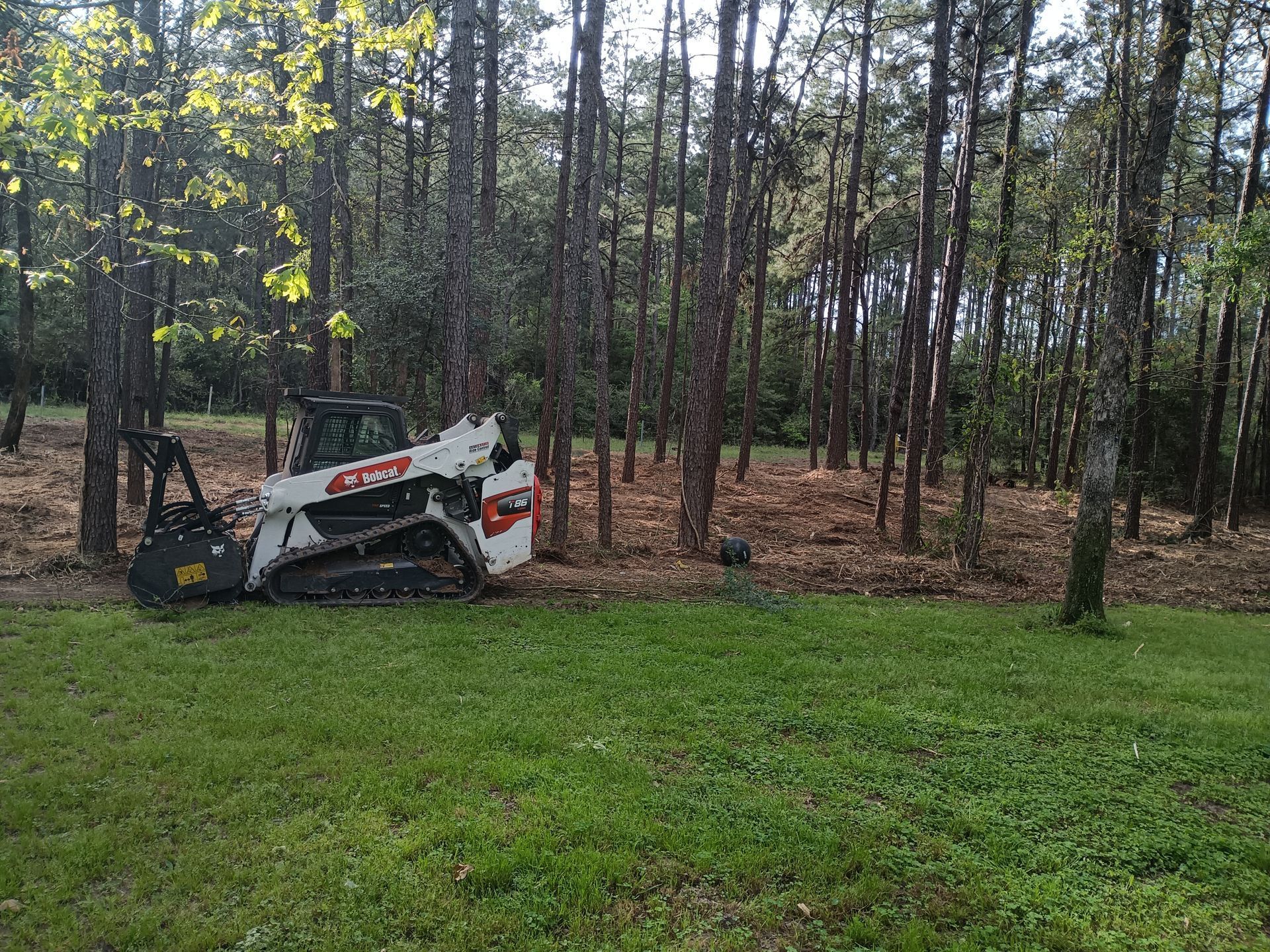 An excavator clearing land and removing brush near Conroe, Texas.