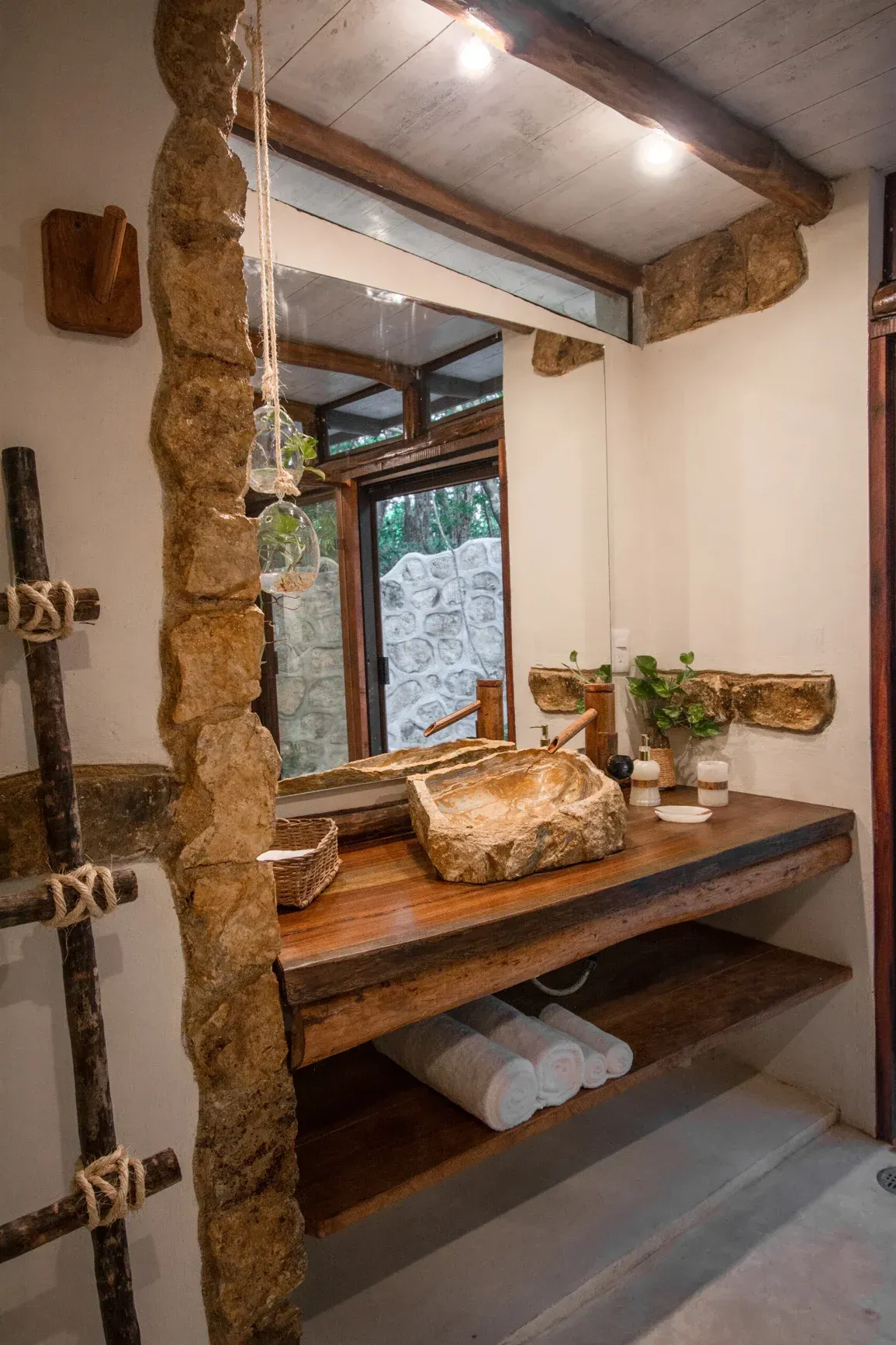 Baño rústico con lavabo de piedra y detalles en madera.