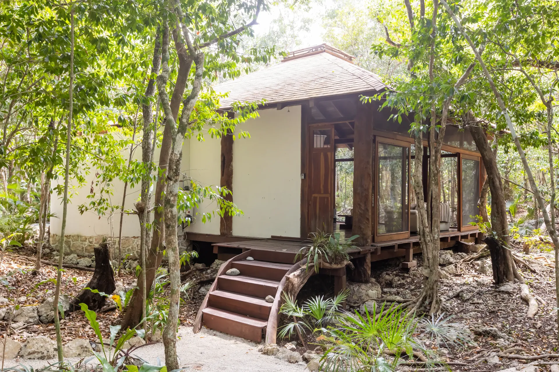 Cabaña rústica con estructura de madera y techo de tejas enclavada en un exuberante bosque verde.