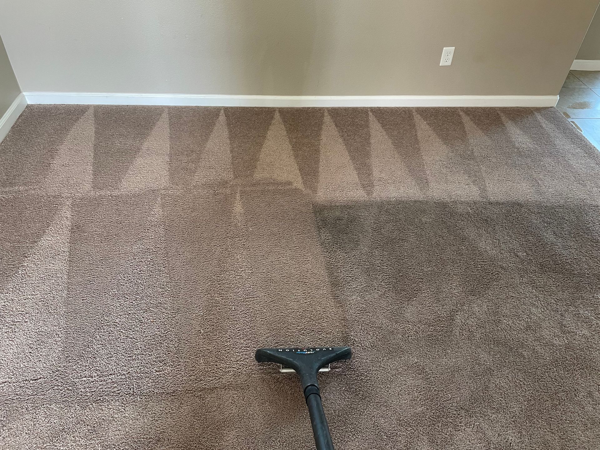 a vacuum cleaner is being used to clean a carpet in a room .
