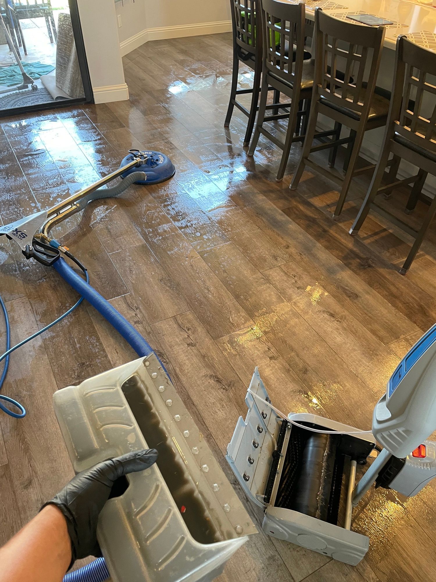 a person is holding a vacuum cleaner in a dining room .