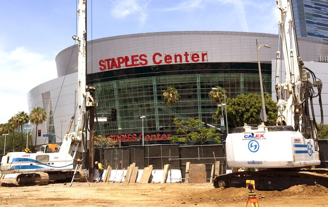 Construction work outside Staples Center with cranes and equipment in front of the building.