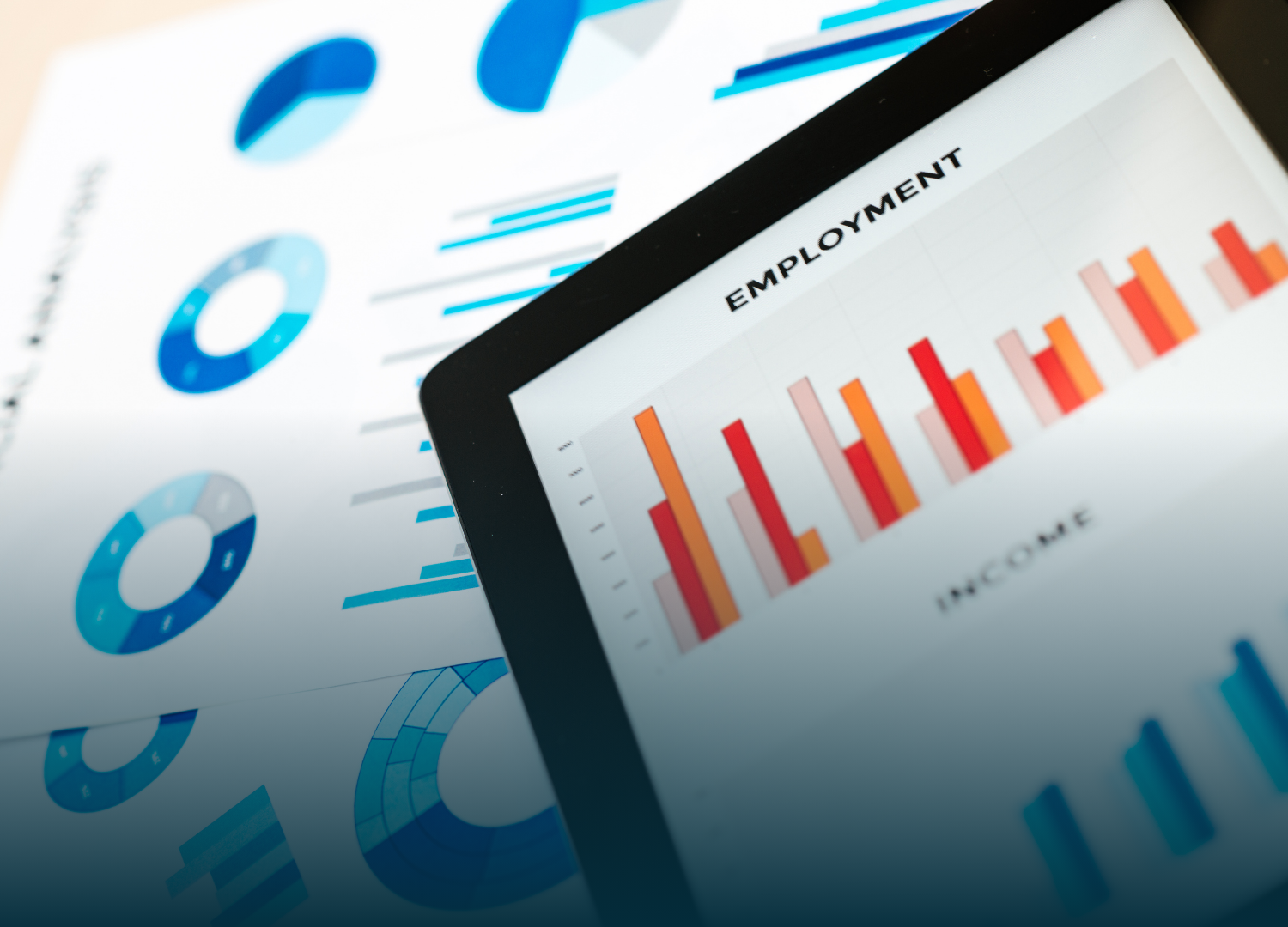 Tablet displaying employment bar graph, with supporting charts in the background, all in blue and orange hues.