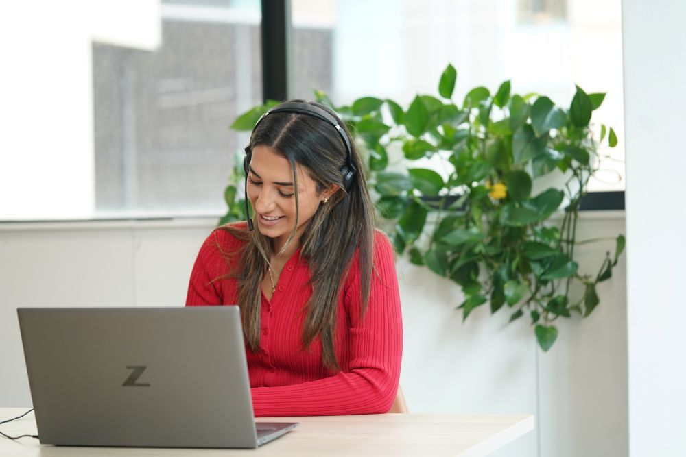 Woman in black top looking at a brochure at a desk, mug on the left.