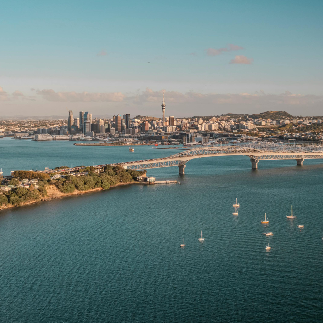 Auckland, New Zealand skyline with harbor and bridge on a sunny day.