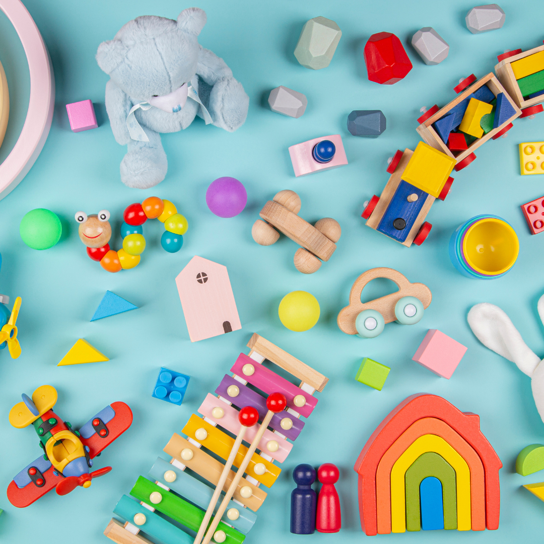 Assortment of colorful wooden toys, including a train, car, xylophone, and rainbow, on a blue background.