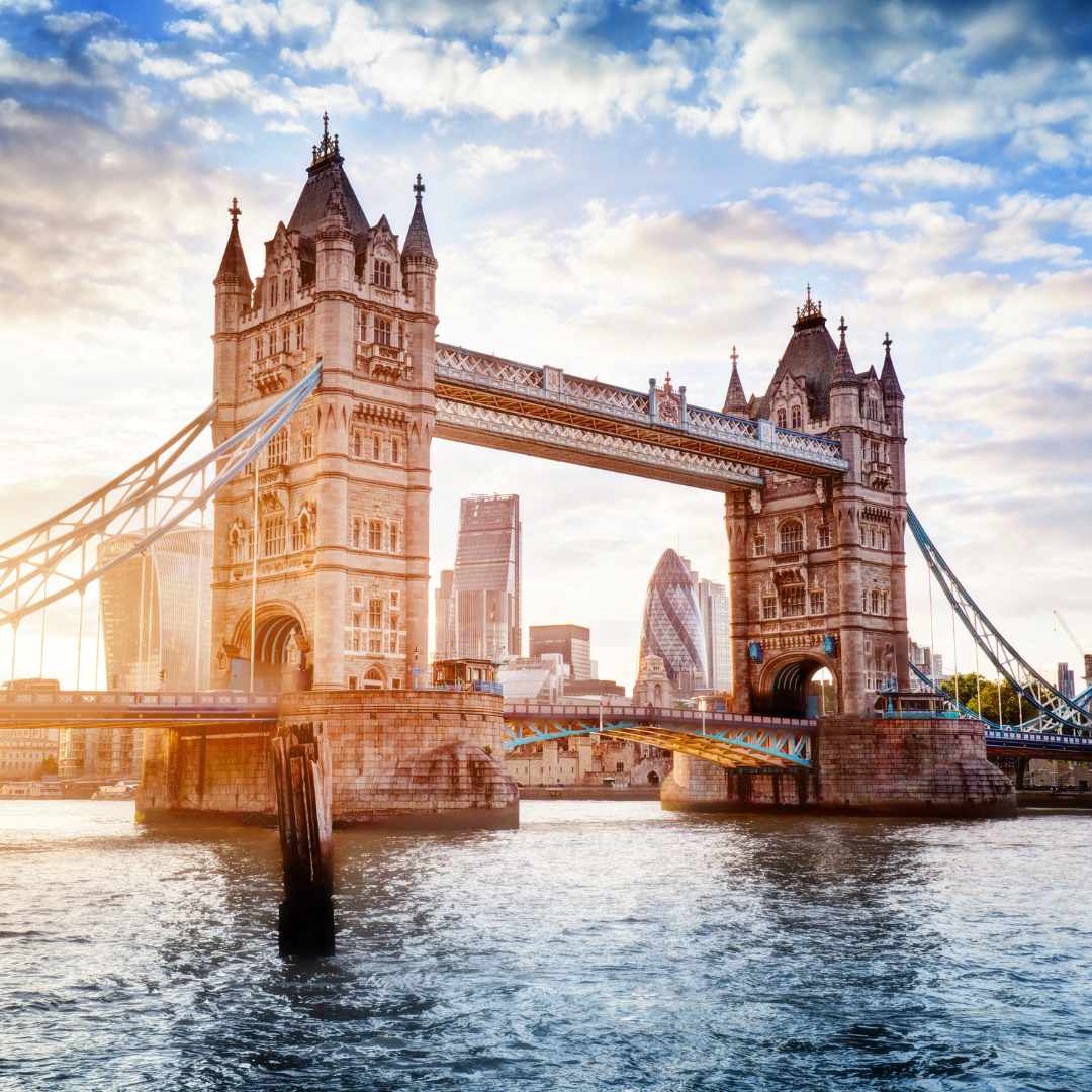 Tower Bridge over the River Thames in London, with city skyline and blue sky.