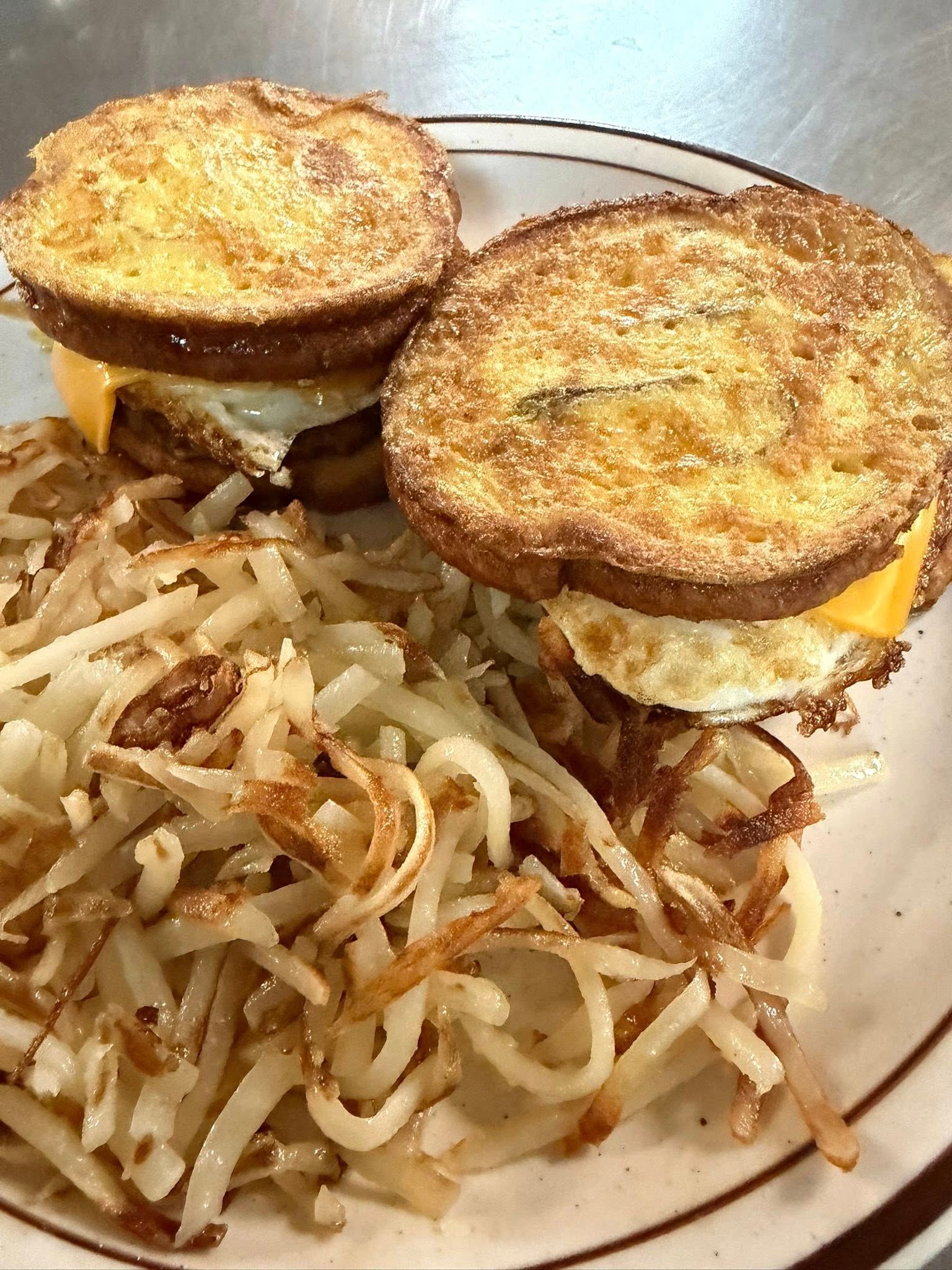 Two fried egg sandwiches served with a side of sautéed onions on a plate
