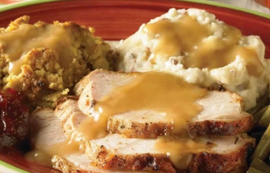 Roast turkey slices with gravy beside mashed potatoes and stuffing on a dinner plate