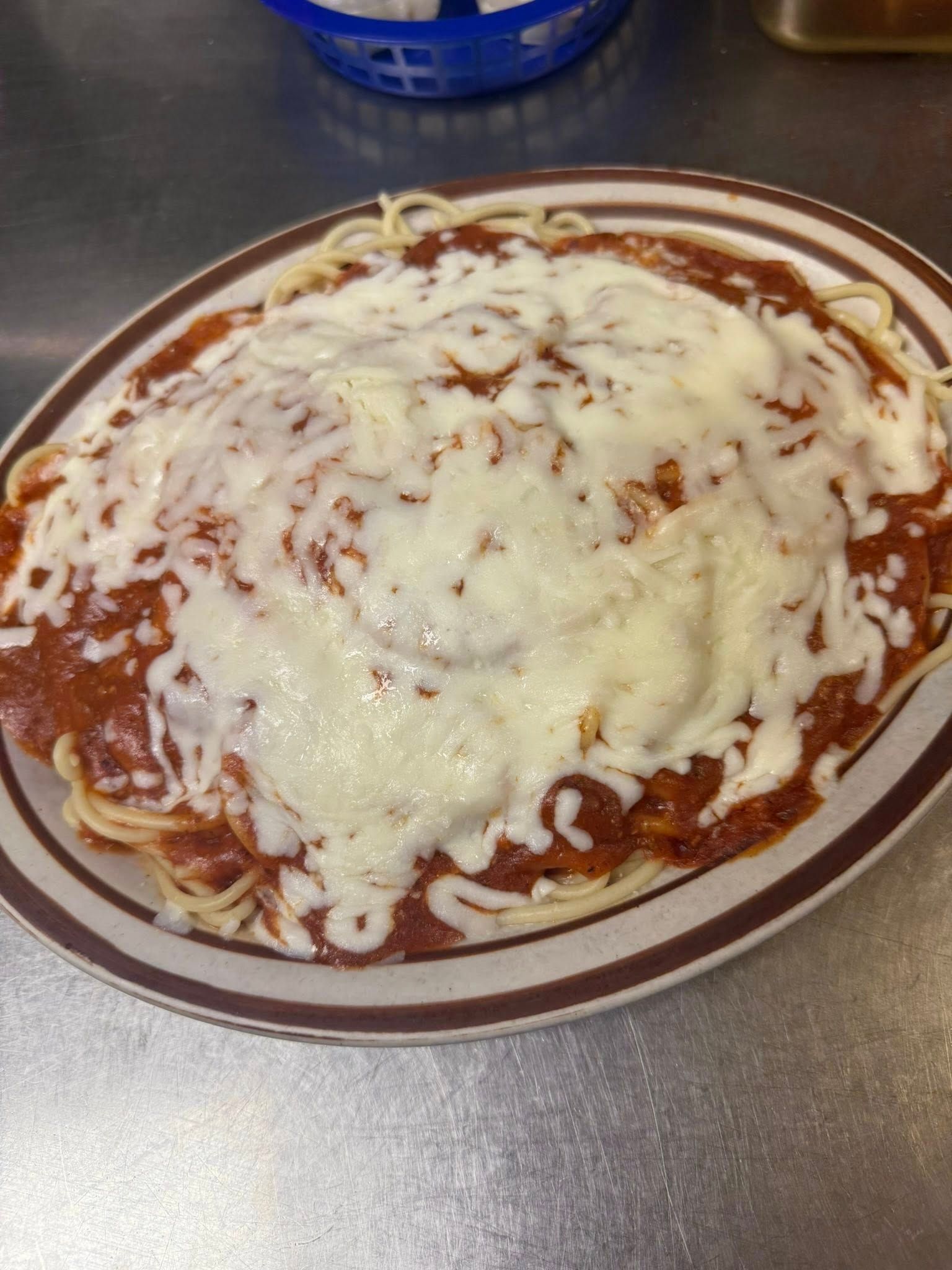 Spaghetti topped with marinara sauce and melted cheese on a plate.