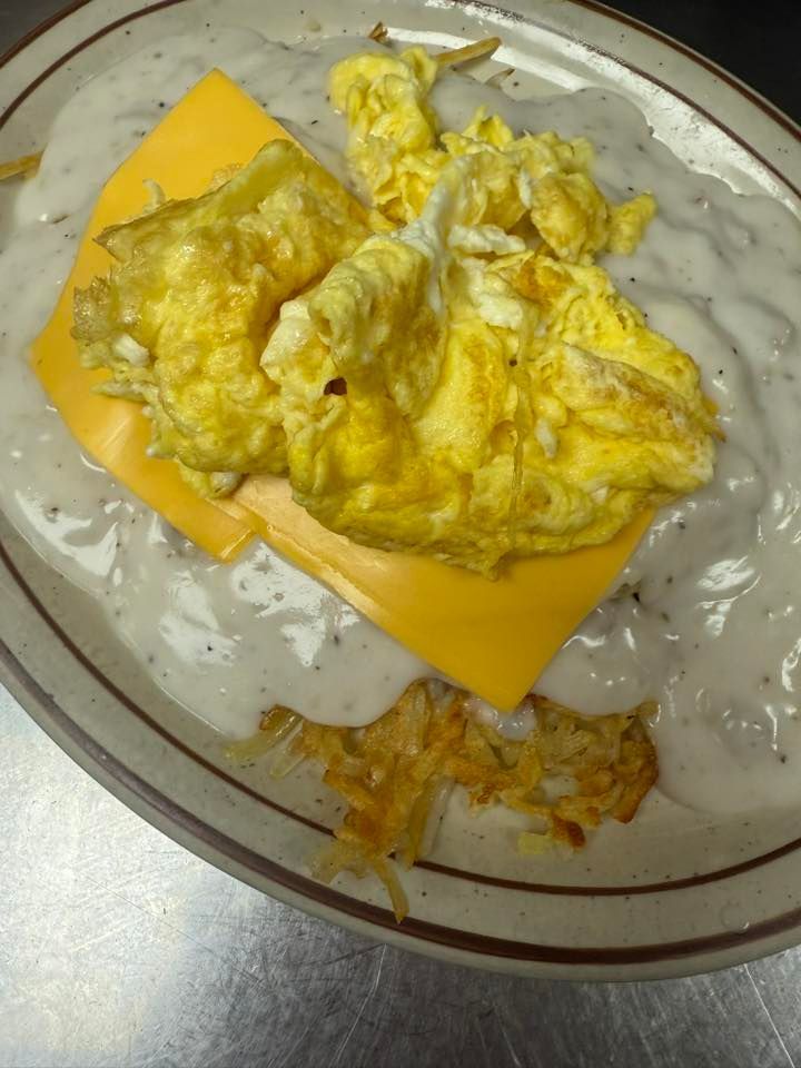 Scrambled eggs on a slice of orange cheese on a white plate with creamy sauce