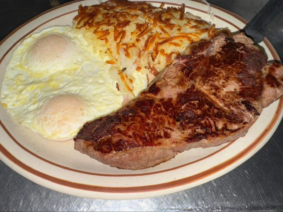 Plate with steak, two fried eggs, and hash browns on a white dish
