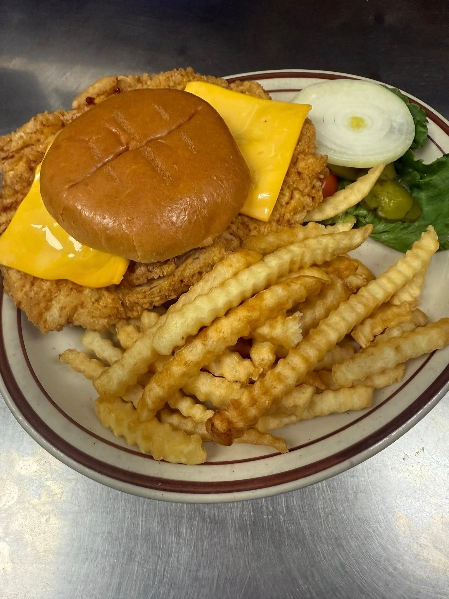 Cheeseburger with crinkle-cut fries and onion slice on a plate