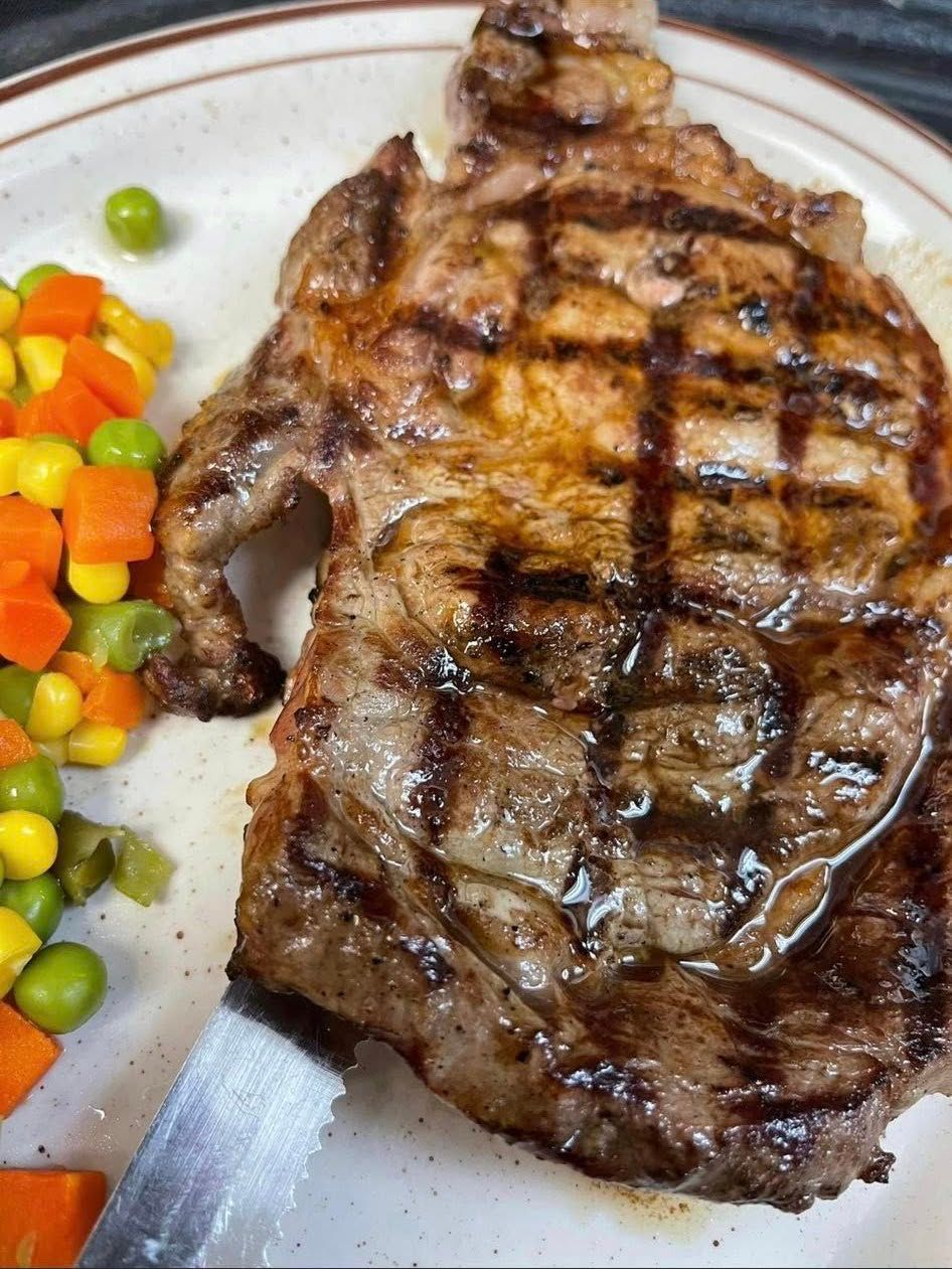 Grilled steak with crosshatch marks beside mixed vegetables on a white plate