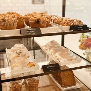 Bakery display with muffins, frosted pastries, and cakes on tiered shelves