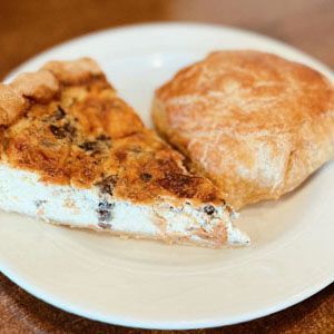 Two slices of pie on a white plate, one browned and one dusted with powdered sugar