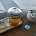 Glass tea pot, empty cup, and small white bowl on a wooden table with a green card.