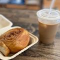 Takeout cinnamon roll and iced coffee in a tray on a wooden table