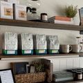 Wooden shelves with coffee bags, mugs, jars, and a wicker basket in a cozy shop display