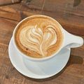 White cup of latte with heart-shaped foam art on a wooden table